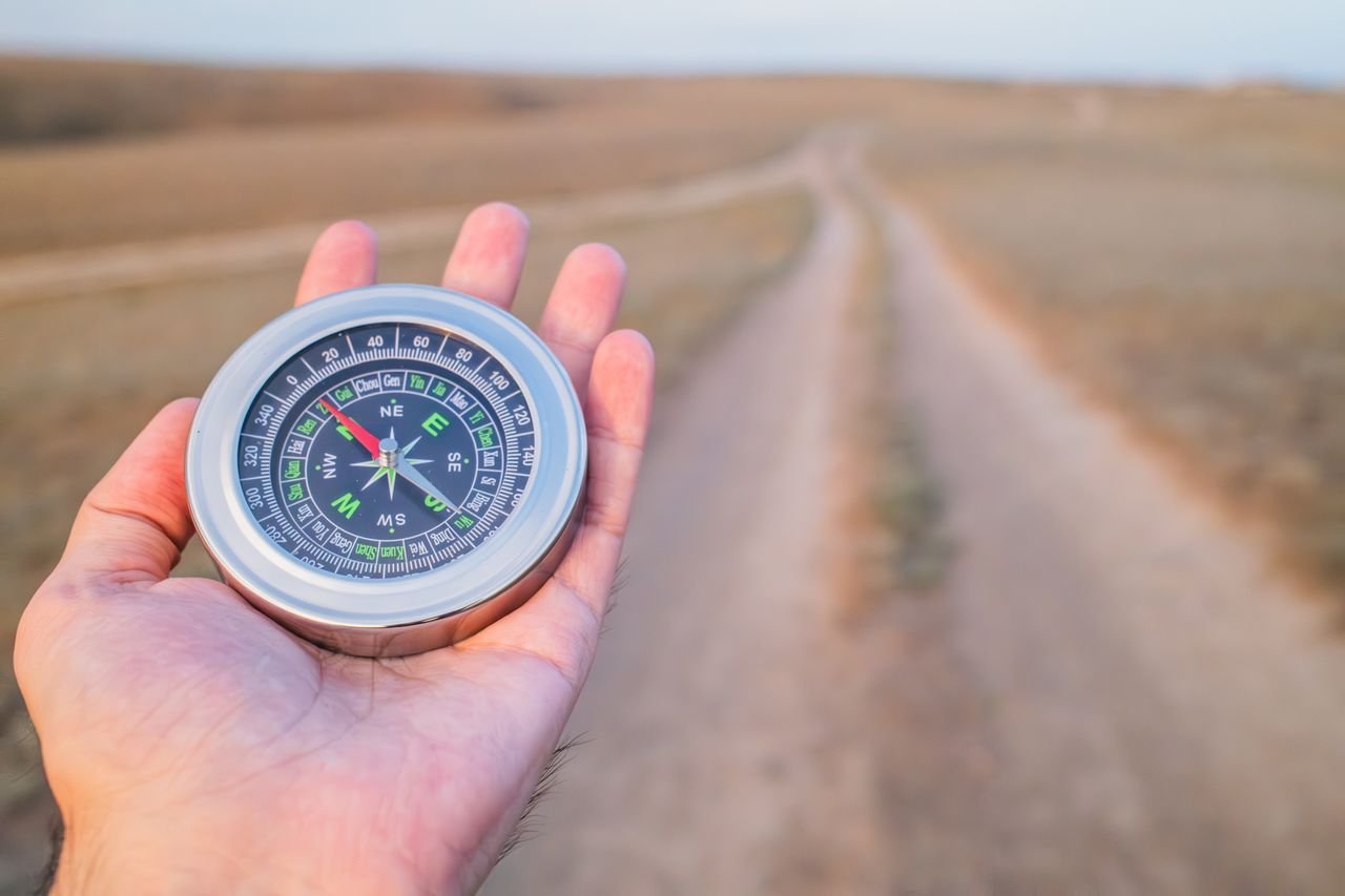 Formação Hand holding a compass guiding along a dusty path outdoors. Perfect for travel and exploration themes.