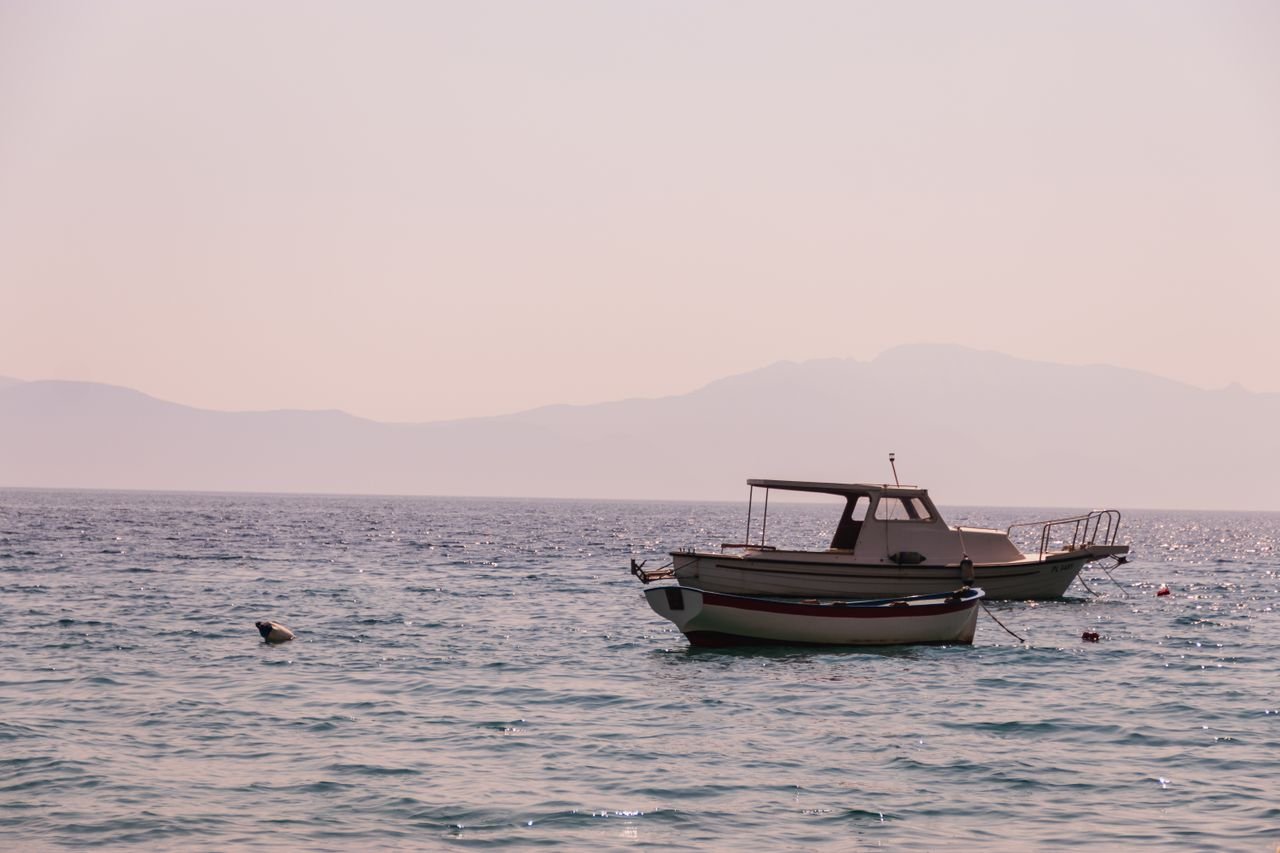 Peaceful scene of boats floating on the Adriatic Sea near Brist, Croatia, with hazy mountains in the background.