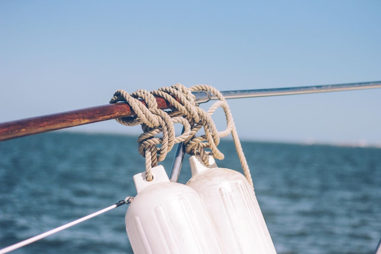 A detailed view of ropes and buoys on a boat over a calm ocean setting.