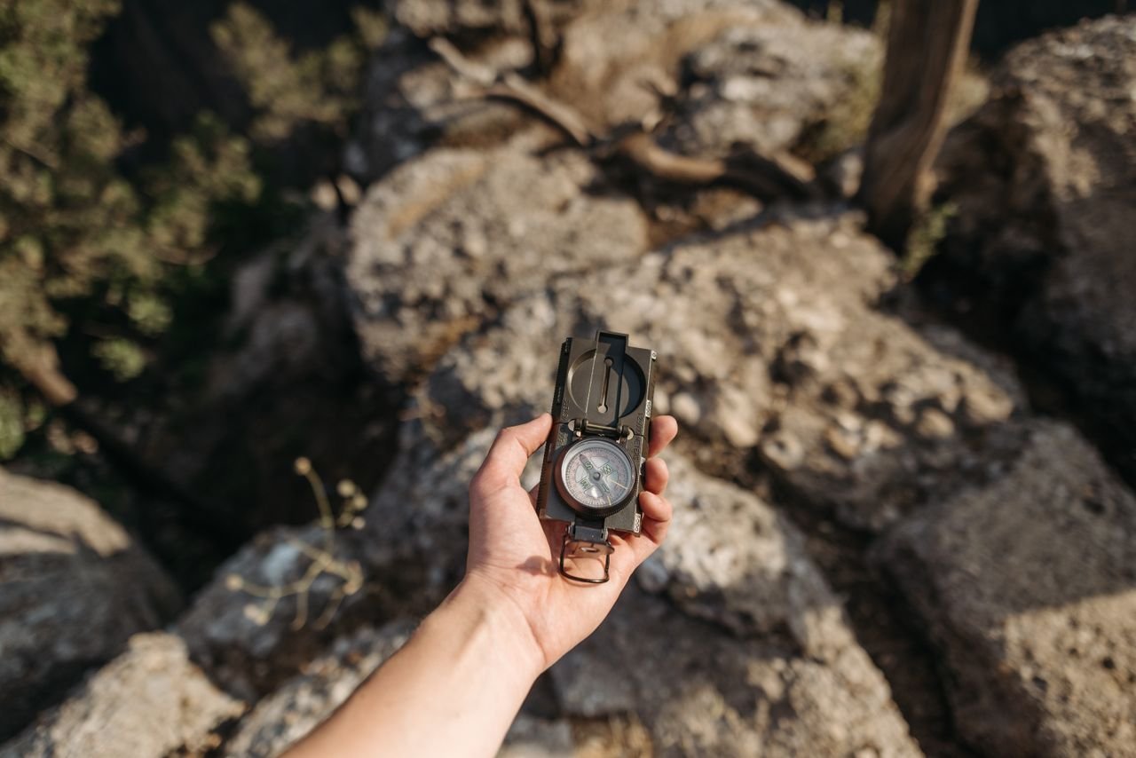 Formação A hand holding a compass over rocky terrain, ideal for navigation themes.
